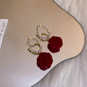 Detail of red flocked rose earrings with sparkling rhinestone gold hoop on velvet background