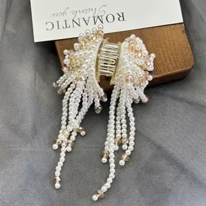 Detailed shot of elegant pearl tassel hair claw with champagne crystals on a mesh fabric