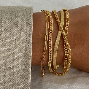 Stack of gold titanium steel bracelets with paperclip, Cuban, and snake chain styles