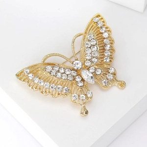 Macro detail of gold butterfly brooch with clear rhinestones and hollow wing design
