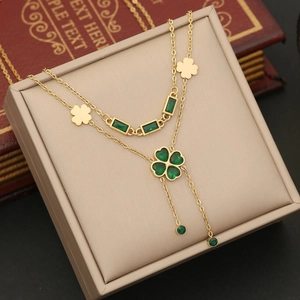 Macro detail of double-layer gold necklace with emerald green heart clover pendants
