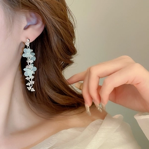 Detail of floral drop earrings featuring light blue resin flowers and crystal tassels