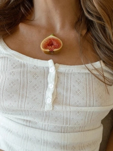 Detail of white pointelle knit pajamas top with buttoned Henley neck and lace texture