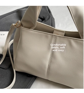 Detail of lychee pattern faux leather texture with gold D-ring and stitching on a beige bag