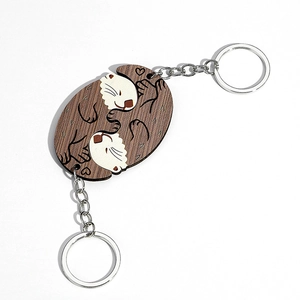 Close-up of paired wooden otter keychains showing detailed wood grain and metal ring