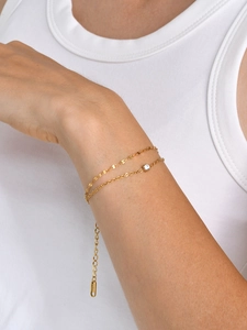 Bracelet double couche plaqué or 18 carats avec zircon clair sur le poignet d'un mannequin