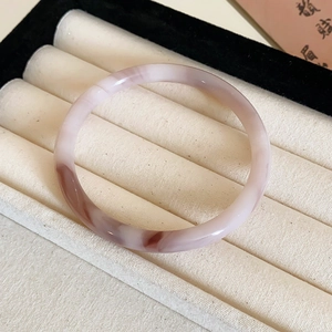 Vue macro d'un jonc en jade rose lotus poli avec des motifs de lavis brun-rougeâtre