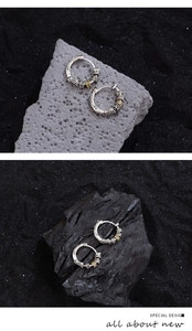 Detailed view of vintage silver hoop earrings with gold rotating rings on charcoal base