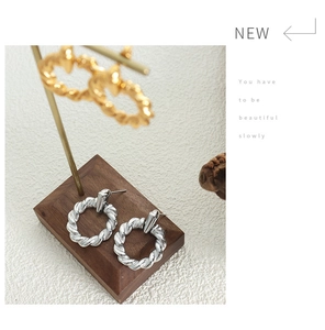 Detail shot of twisted rope texture hoop earrings in polished gold and silver finish