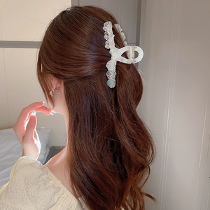 Vue détaillée d'une pince à cheveux irisée sur cheveux ondulés pour un look d'été