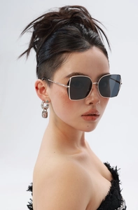 Detail of oversized square sunglasses with gold metal frame and dark grey nylon lenses