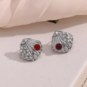 Macro shot of silver shell stud earrings with red gemstone and sparkling rhinestones