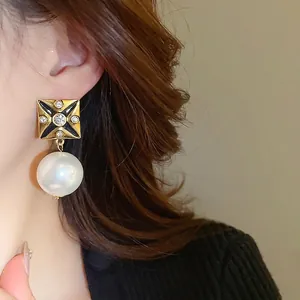 Vintage style square gold earrings with black enamel star and white hanging pearl