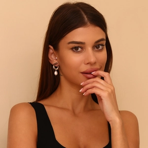 Detailed close-up of a silver irregular geometric earring with a white faux pearl on a model