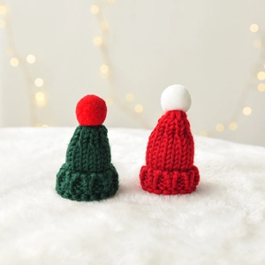 Red and green knitted mini Christmas hats with pom-poms for festive holiday decorations