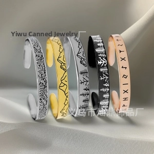 Detail view of five different C-shaped stainless steel cuffs in gold, black, and silver