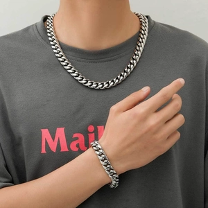 Gros plan d'un collier et bracelet gourmette en acier argenté sur un mannequin