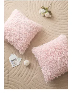 Detail of two pink plush faux fur pillow covers set on a textured beige rug