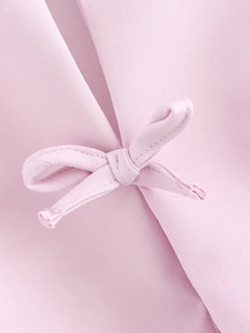 Detailed close-up of a delicate pink bow tie design on a soft halter top garment
