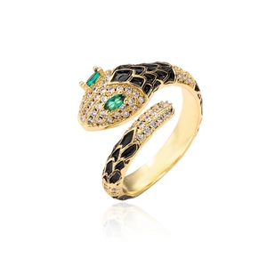 Gold-plated snake ring with green eye stones and black enamel patterns on white background