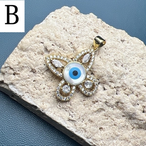 Detailed view of a gold butterfly charm with zircon paving and a central evil eye element