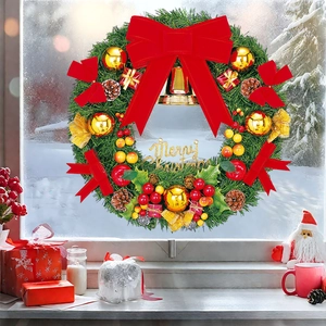Christmas wreath with red bow, pine cones, and Merry Christmas sign on a snowy window