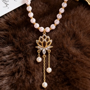 Detail of a French vintage pearl necklace with a gold lotus pendant and hanging tassels