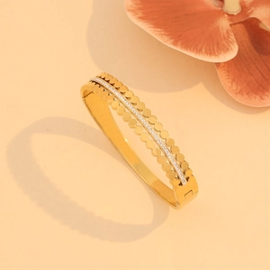 Detail of gold multilayer stainless steel bangle featuring hollow patterns and micro-pavé crystals