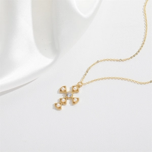 Minimalist gold cross necklace with pearl and zircon inlay on white silk background