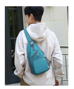 Detail view of teal crossbody bag showing fabric texture, zipper pocket, and mesh compartment