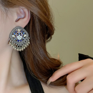Detail of bohemian silver Jhumka earrings with blue floral enamel and metal tassels