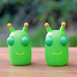 Macro shot of two green alien squeeze toys with orange antennae on a wooden surface