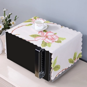 Detailed view of white linen microwave cover featuring pink magnolia patterns and wavy edges
