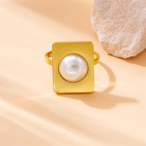 Golden geometric square ring with round white pearl inlay on elegant peach background