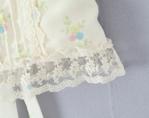 Gros plan sur tissu floral avec détails de bordure en dentelle brodée blanche