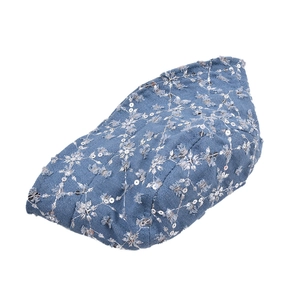 Close-up of denim fabric with silver sequin snowflakes and embroidered details