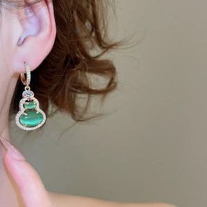 Close-up of 14k gold-plated Wulu earring with green resin and micro-pave crystals