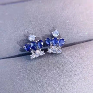 Macro shot of crown-shaped stud earrings with sapphire blue stones and white diamonds