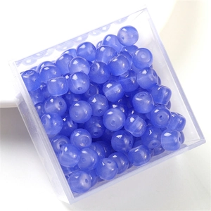 Macro shot of blue translucent round glass beads in a clear storage box for DIY jewelry