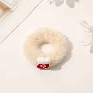 Close-up of beige plush Christmas scrunchie featuring a red snowflake glove charm