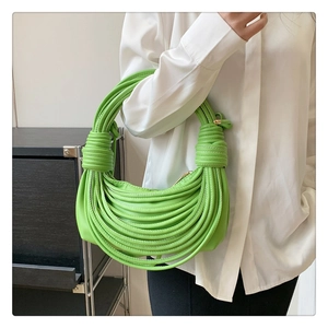 Detail view of a bright green woven knot shoulder bag with a unique leather wrap texture