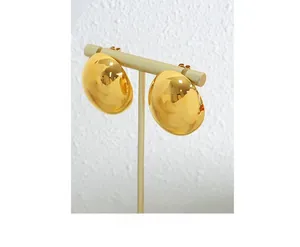Polished gold semi-sphere earrings displayed on a metallic T-stand with a clean white backdrop