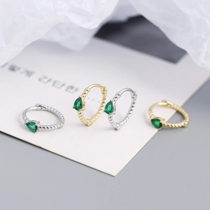 Macro view of S925 silver twist huggie earrings with pear-shaped green gemstones
