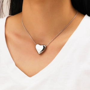 Collier à pendentif cœur argenté poli avec chaîne serpent sur un haut blanc en V