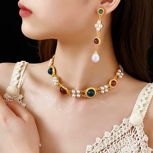 Detail showing vintage gold jewelry set with pearls and gemstones on a model
