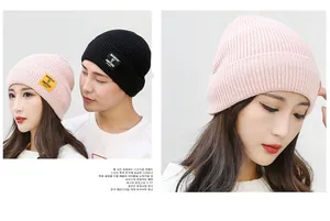 Detail of ribbed knit beanies in black and pink with Moment of Ambitions patch