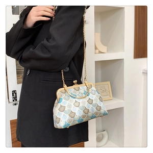 Detail of vintage blue patterned fabric handbag with gold metal frame and chain strap