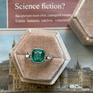 Silver ring with emerald cut green stone in a pink velvet hexagon jewelry box