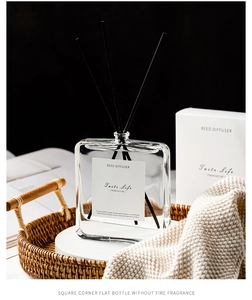 Modern square glass reed diffuser bottle with black sticks on a woven tray set