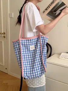 Borsa tote in tela a quadretti bianchi e blu con spalline rosa su una modella